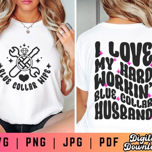 May include: A white t-shirt with a black design of a wrench and screwdriver crossed over a ring with a diamond. The text "Blue Collar Wife" is written around the design. The back of the shirt has the text "I Love My Hard Workin' Blue Collar Husband" in black with pink glitter accents.