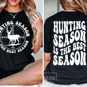 May include: Black t-shirt with the text "HUNTING SEASON IS THE BEST SEASON" in white. The front of the shirt features a white deer silhouette inside a scope. The back of the shirt has the same text in a wavy font.