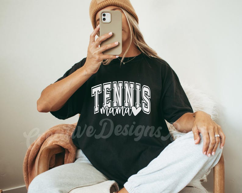 May include: Black t-shirt with white text that says "Tennis Mama" with a small heart graphic.