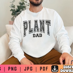 May include: A white long-sleeved sweatshirt with the text "PLANT DAD" in black letters.