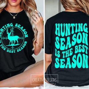May include: Black t-shirt with the text "HUNTING SEASON IS THE BEST SEASON" in turquoise. The front of the shirt features a deer silhouette inside a crosshair target. The back of the shirt has the same text in a retro font.