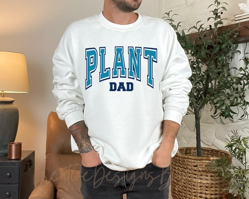 May include: White sweatshirt with blue text that reads "PLANT DAD" in a varsity style font.
