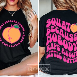 K&ouml;nnte beinhalten: Schwarzes T-Shirt mit einem rosafarbenen Pfirsich-Motiv und dem Text "Squat because nobody raps about little butts" in einer Retro-Schrift.