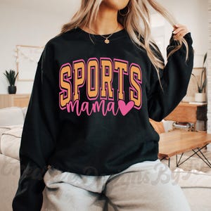 May include: Black sweatshirt with the text "SPORTS mama" in yellow and pink letters with a pink heart.
