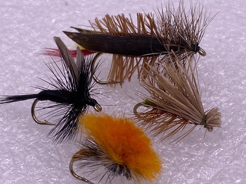 May include: Four different fly fishing lures with brown, black, and orange feathers.