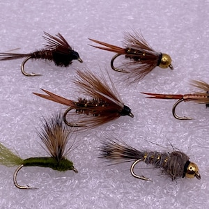 May include: Five different fly fishing lures with brown, gold, and green feathers and a black head. The lures have gold beads on the end of the hook.