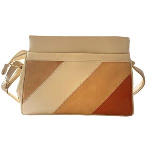 May include: A beige and tan shoulder bag with a diagonal color block design. The bag features a cream-colored top and strap, with a zipper closure. The color block design includes shades of beige, tan, and brown.