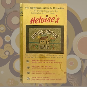 May include: A yellow book titled "Heloise's Housekeeping Hints" with a picture of a house on the cover. The book cover has text that says "Over 350,000 copies sold in the £3.95 edition...the greatest timesaver for the homemaker since TV dinners."