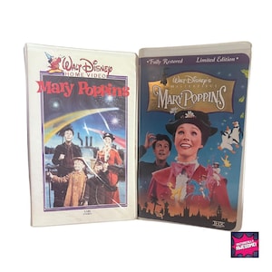 Może przedstawiać: Dwie kasety VHS z klasycznym filmem Disneya Mary Poppins. Kaseta po lewej to standardowe wydanie VHS, podczas gdy kaseta po prawej to limitowana edycja, w pełni odrestaurowana. Obie kasety przedstawiają ikoniczny obraz Mary Poppins stojącej na dachu z pingwinem i innymi postaciami.