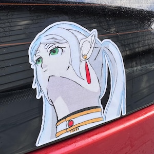 May include: A sticker featuring a stylized anime-style character with long, light blue hair and green eyes. The character has pointed ears and is wearing a gold and red earring and a gold collar. The sticker is on a red surface.