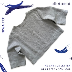 May include: A gray Niwa Tee shirt with short sleeves. The shirt is made of a soft, textured fabric. The text "NIWA TEE" is printed vertically on the left side of the image, and the word "allotment" is printed at the top. Sizes available: XS, S, M, L, XL, XXL.