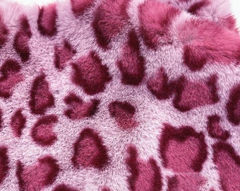 Puede incluir: Primer plano de una tela de piel sintética rosa y burdeos con estampado de leopardo.