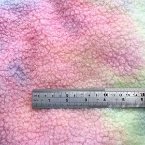 May include: A close-up of a soft, pink, green, and purple tie-dye fabric with a ruler measuring 15 inches.