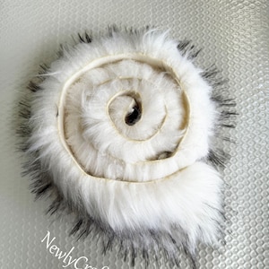 Peut inclure: Une garniture en fausse fourrure blanche avec une bordure noire. La fourrure est enroulée en forme de spirale.