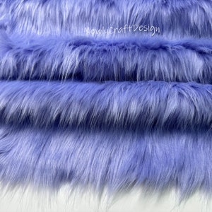 May include: Close-up of a soft, plush fabric in a light lavender color. The fabric has a long, fluffy pile and is perfect for crafting projects.