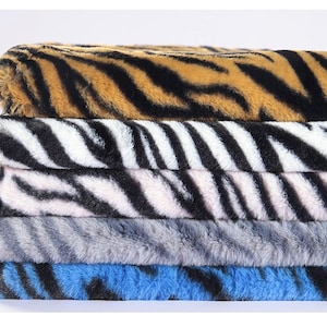 May include: A stack of five fabric swatches with different animal print patterns. The top swatch is a brown and black tiger print, followed by a black and white zebra print, a pink and black zebra print, a gray zebra print, and a blue and black zebra print.