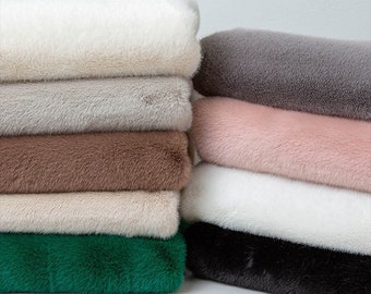 Peut inclure: Une pile de tissu en fausse fourrure de différentes couleurs, dont le blanc, le gris, le rose, le marron, le beige, le vert et le noir.