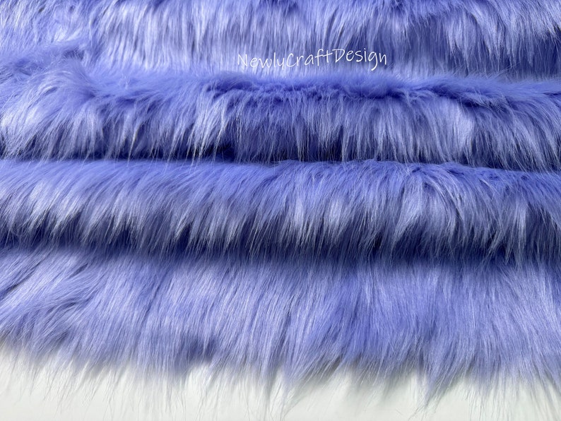 May include: Close-up of a soft, plush fabric in a light lavender color. The fabric has a long, fluffy pile and is perfect for crafting projects.