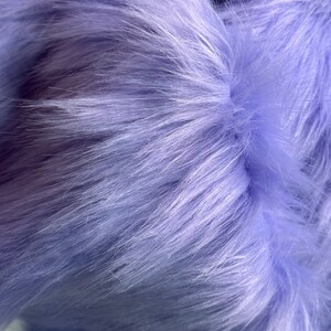May include: Close-up of soft, light purple faux fur fabric. The fur is very fluffy and has a subtle sheen.