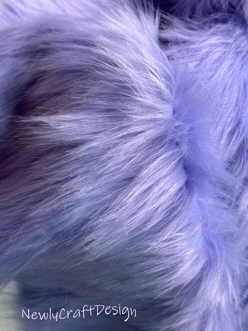 May include: Close-up of soft, light purple faux fur fabric. The fur is very fluffy and has a subtle sheen.