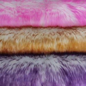 Könnte beinhalten: Drei Schichten Kunstfellstoff in Pink, Braun und Lila. Der Stoff hat eine weiche, flauschige Textur.