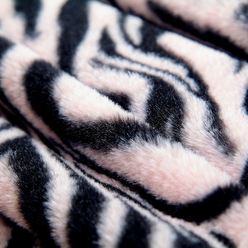 May include: Close-up of a pink and black faux fur fabric with a zebra stripe pattern.