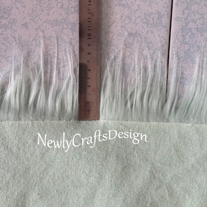 May include: A close-up of a light green fabric with a white faux fur trim. A ruler is visible in the image, showing the fur trim is approximately 7 inches long. The text "Newly Crafts Design" is visible at the bottom of the image.