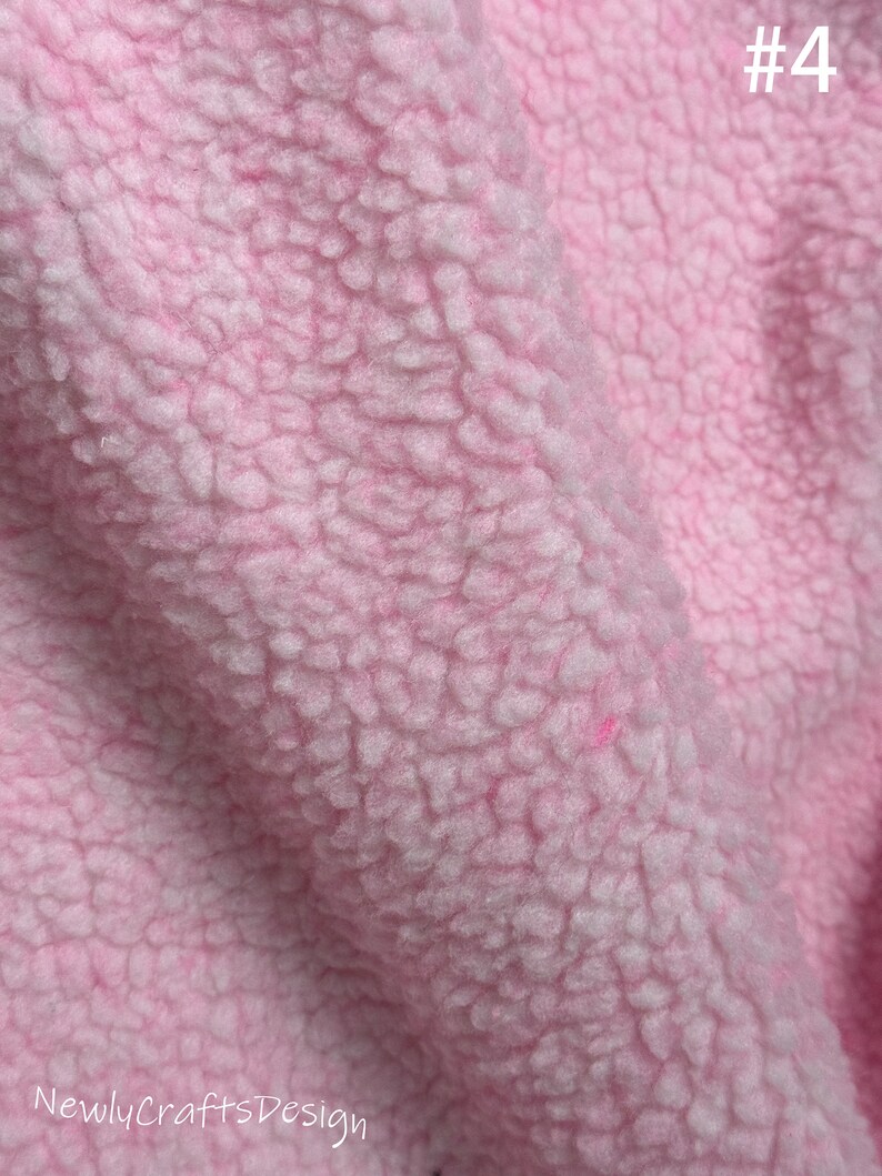 May include: Close-up of a soft, pink, fuzzy fabric with a textured surface. The fabric is a type of fleece.