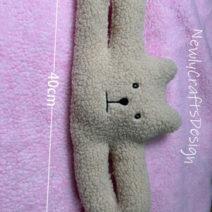 May include: A beige plush toy shaped like a bear with a black nose and eyes. The toy is 16 inches wide and 40 inches tall.  "NewlycraftsDesign" is written on the right side of the image.