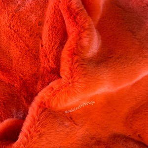 Peut inclure: Gros plan sur un tissu en fausse fourrure orange vif. Le tissu est doux et moelleux, avec un léger brillant. #12