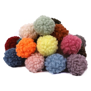 Puede incluir: Un montón de pompones peludos y coloridos en varios tonos de rojo, naranja, amarillo, verde, azul, morado y marrón. Los pompones están hechos de un material suave y esponjoso y son perfectos para proyectos de manualidades.