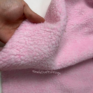May include: Close-up of a soft, pink, fuzzy fabric. The fabric has a textured, fluffy surface.