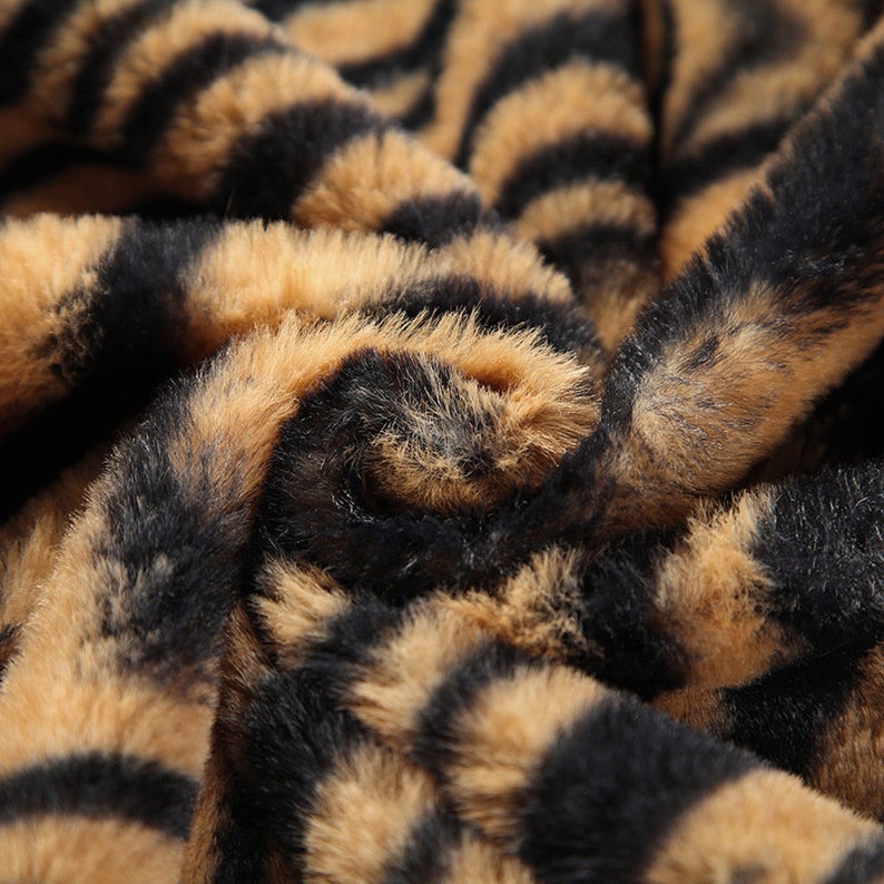 May include: Close-up of a brown and black faux fur fabric with a tiger stripe pattern.