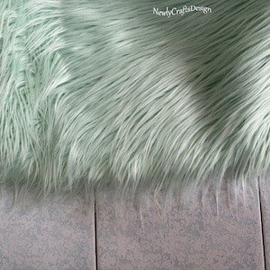 May include: A light green faux fur rug with a soft, fluffy texture.