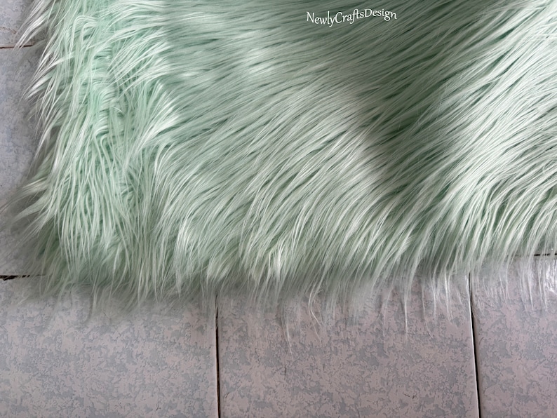 May include: A light green faux fur rug with a soft, fluffy texture.