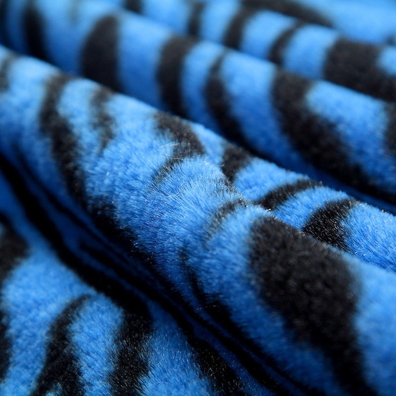 May include: Close-up of a blue and black faux fur fabric with a zebra stripe pattern.