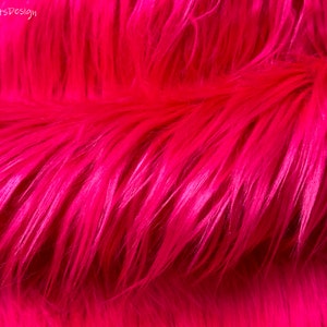 Può includere: Primo piano di un tessuto in pelliccia sintetica rosa brillante. La pelliccia è morbida e soffice, con un pelo lungo. Il tessuto è perfetto per progetti di artigianato, come coperte, cuscini e abbigliamento.