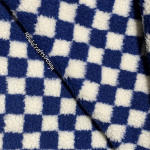Peut inclure: Tissu à carreaux bleus et blancs avec une texture duveteuse. Le tissu est plié en deux et le texte "NewlycraftsDesign" est visible dans le coin inférieur gauche. Le numéro "#11" est visible dans le coin supérieur droit.