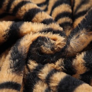 May include: Close-up of a brown and black faux fur fabric with a tiger stripe pattern.