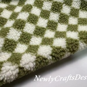 May include: Green and white checkered fabric with a fuzzy texture. The fabric is soft and plush, perfect for making blankets, pillows, or other home decor items.