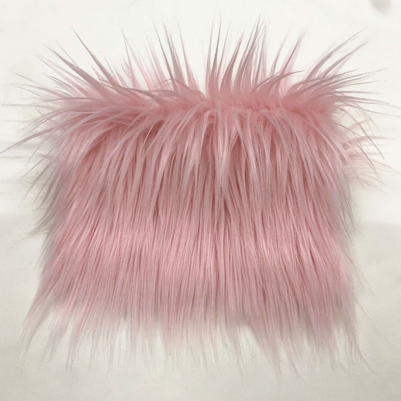 May include: A close-up of a pink fluffy fabric. The fabric has a soft, plush texture and is perfect for crafting projects.