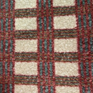 Könnte beinhalten: Nahaufnahme eines weißen Stoffes mit einem rot-grün-braunen Karomuster. Der Stoff hat eine flauschige Textur.