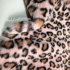 Pode incluir: Tecido de pele sintética rosa com um padrão de leopardo marrom e preto.