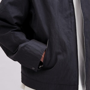 K&ouml;nnte beinhalten: Schwarze Jacke mit Rei&szlig;verschluss und einer Tasche auf der linken Seite. Die Jacke hat einen Knopfverschluss an der Tasche und einen silbernen Rei&szlig;verschluss. Die Jacke ist aus leichtem Material gefertigt.