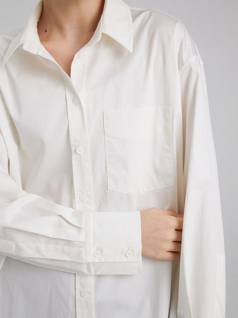 Pu&ograve; includere: Una camicia bianca a maniche lunghe con bottoni, una tasca sul petto e polsini con bottoni.