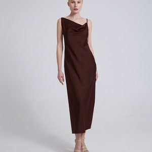 Op de afbeelding: Een bruine maxi-jurk zonder mouwen met een cowl-hals en een rechte silhouet.