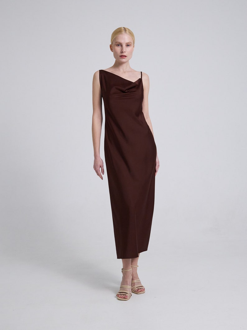 Op de afbeelding: Een bruine maxi-jurk zonder mouwen met een cowl-hals en een rechte silhouet.