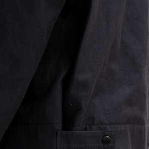 K&ouml;nnte beinhalten: Nahaufnahme einer schwarzen Jacke. Die Jacke hat ein gekn&ouml;pftes Manschettendetail und einen Knopfverschluss. Der Stoff scheint matt zu sein. Die Jacke ist wahrscheinlich Teil einer Bekleidungskollektion.