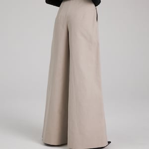 May include: Wide-leg pants in a light beige color. The pants have a high waist and a relaxed fit.