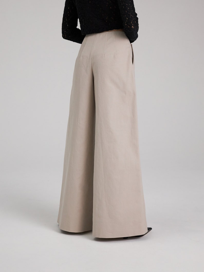 May include: Wide-leg pants in a light beige color. The pants have a high waist and a relaxed fit.